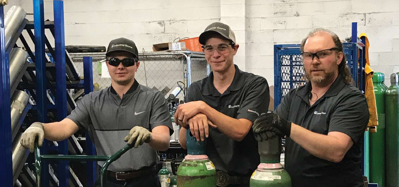 Three Industrial Source operations team members in the cylinder-handling area